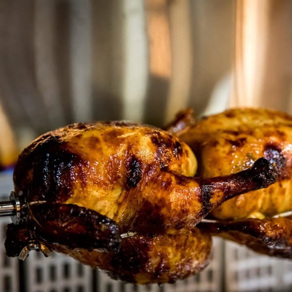 Two whole roasted chickens with crispy, golden-brown skin on a rotisserie at Hên Vietnamese Restaurant.