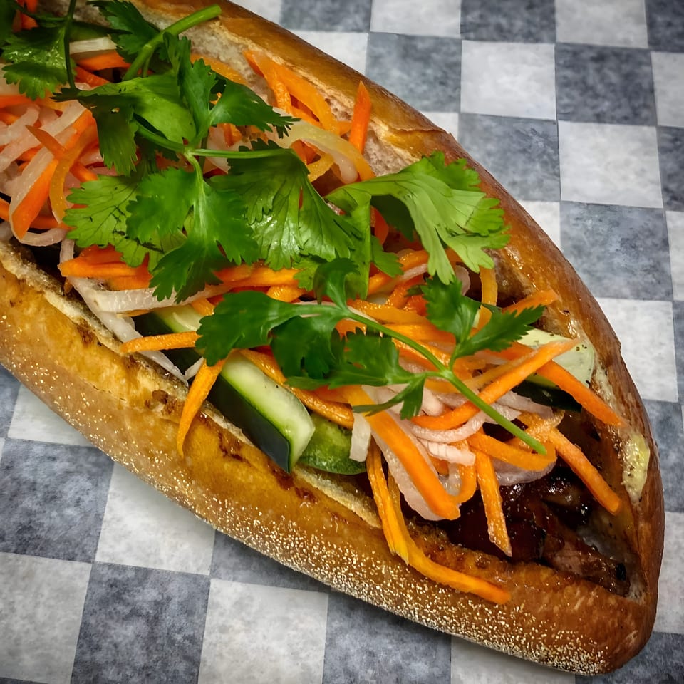A Hên Vietnamese Restaurant banh mi sandwich filled with meat, pickled carrots, daikon, cucumber, and cilantro.