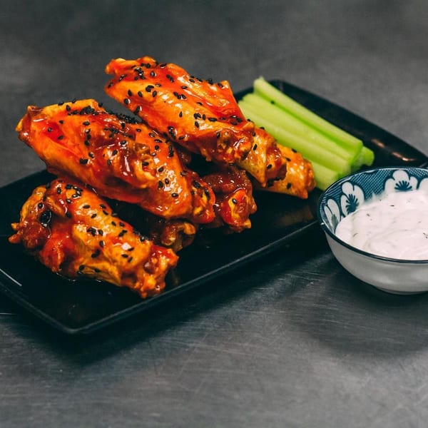 Hên Vietnamese Restaurant's spicy chicken wings with black sesame seeds, celery sticks, and ranch dip.