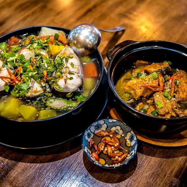 Two Vietnamese dishes, one with fish and vegetables, the other with braised pork, and a chili dipping sauce.