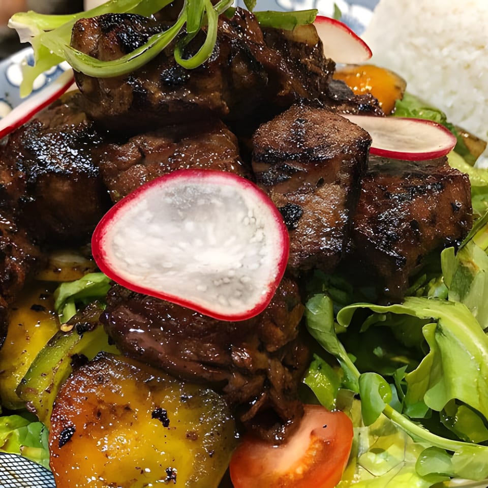 Close-up of Hên Vietnamese Restaurant's shaking beef with bell peppers, radishes, and greens.