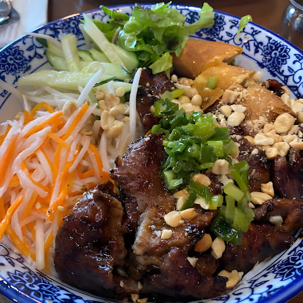 Hên Vietnamese Restaurant's vermicelli bowl with grilled pork, spring rolls, fresh vegetables, and peanuts.