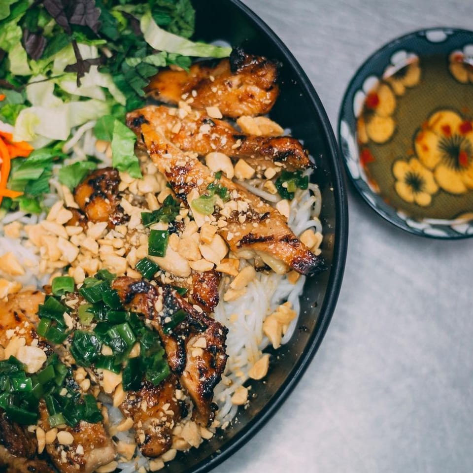 Hên Vietnamese Restaurant's grilled chicken vermicelli bowl with peanuts, scallions, and a side of sauce.